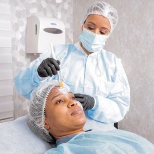 A beautician applies a treatment to a woman's face in a spa, focusing on skincare.