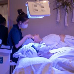Patients receiving LED light therapy and facial treatment in a spa setting.