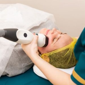 A woman receiving professional facial treatment at a clinic, highlighting beauty and technology.